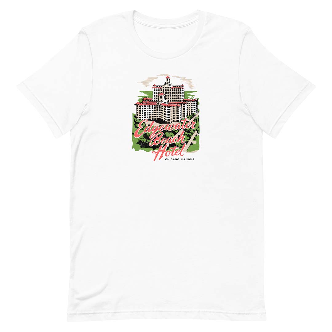 A white short-sleeve crewneck t-shirt featuring a colorful graphic print of the Edgewater Beach Hotel over a green background.