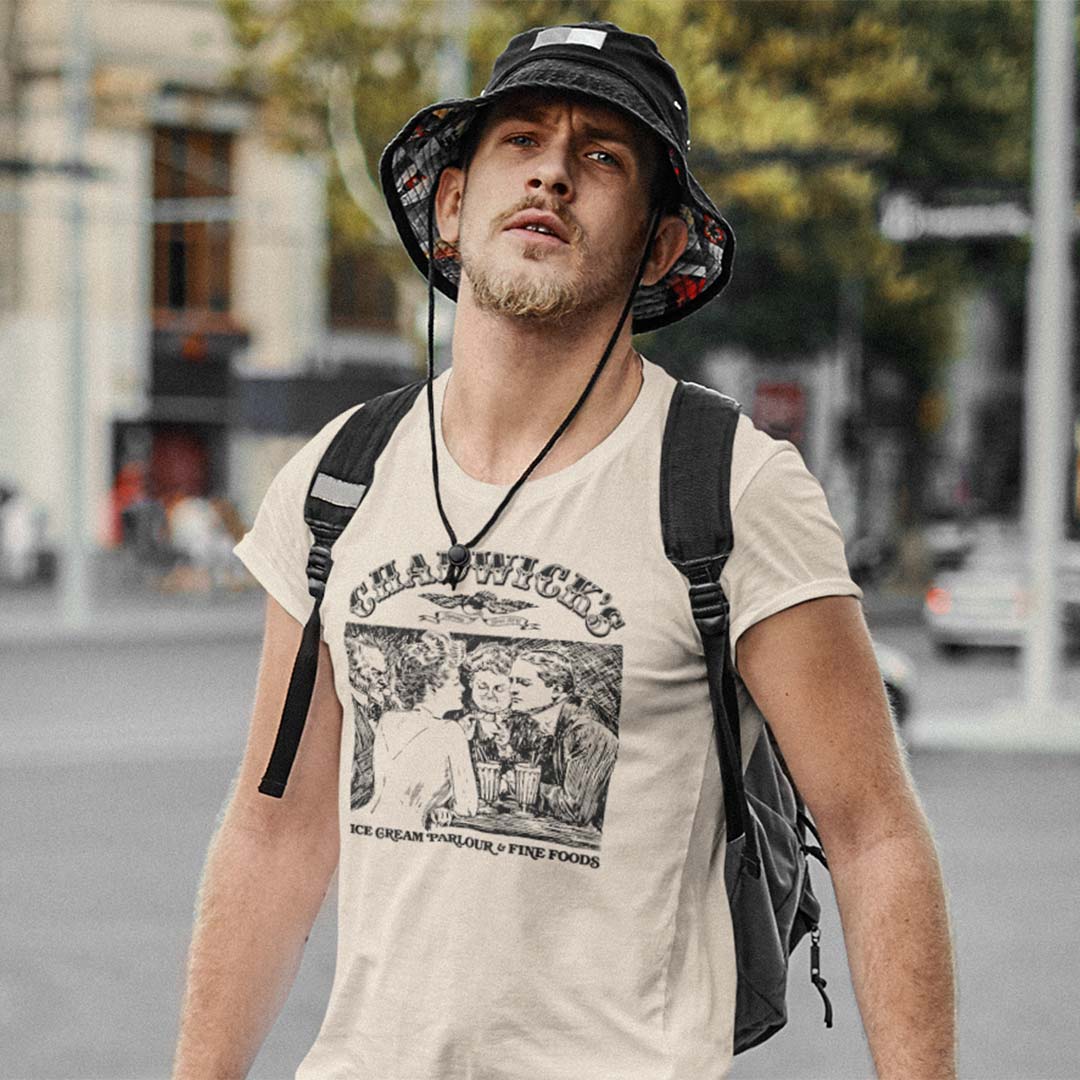 A cream-colored short-sleeve t-shirt with a black graphic print on the front. The graphic features the text 'CHADWICK'S' above an illustration of people eating ice cream, with 'ICE CREAM PARLOUR & FINE FOODS' printed below.