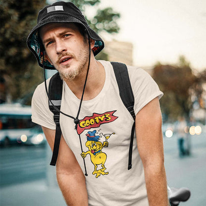 A man wearing a black bucket hat and a cream-colored t-shirt with a retro yellow cartoon graphic that reads 'Goochy's'. He is outdoors on a city street with a blurred background.