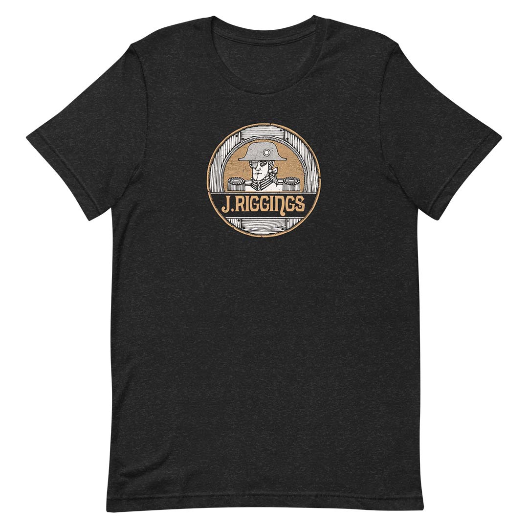 A dark heather gray short-sleeve t-shirt with a circular vintage-style graphic on the chest featuring a cowboy illustration and the text 'J. RIGGINGS'.