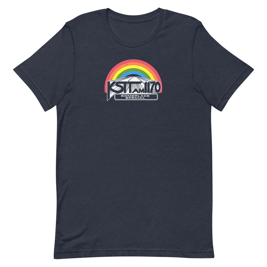 A navy blue short-sleeve t-shirt with a graphic on the chest featuring a rainbow arch over a mountain and the text 'KSTT AM 1170' and 'SOMEPLACE SPECIAL'.