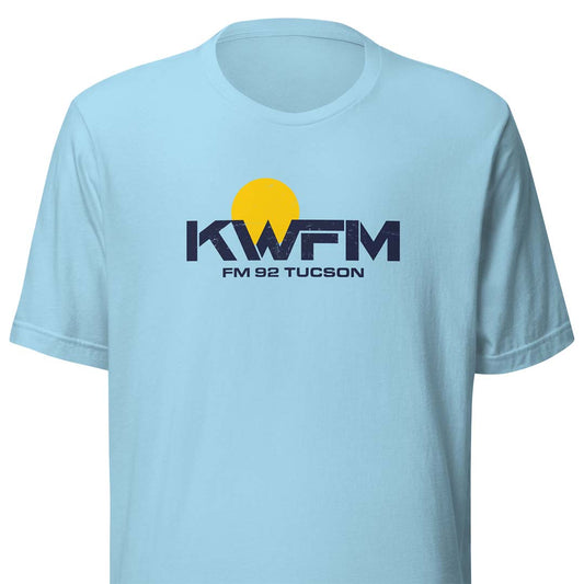 A light blue short-sleeve crewneck t-shirt featuring a yellow and navy blue 'KWFM FM 92 TUCSON' graphic printed on the chest, displayed against a solid white background.