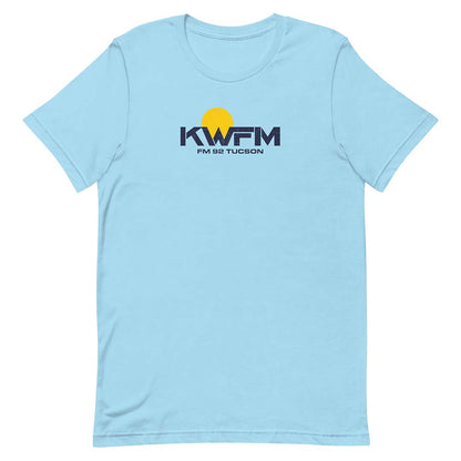 A light blue short-sleeve crewneck t-shirt featuring a 'KWFM FM 92 TUCSON' logo with a yellow sun graphic on the chest, displayed on a clean white background.