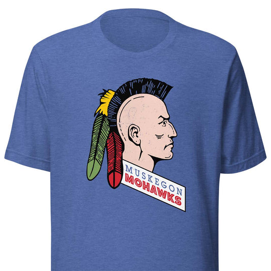 A heather blue short-sleeve t-shirt featuring a vintage-style graphic of a Native American profile with a black mohawk, red and green feathers, and a banner reading 'MUSKEGON MOHAWKS'.
