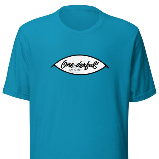 A bright turquoise blue short-sleeve t-shirt with a white and black graphic on the chest. The graphic is shaped like an eye and contains the text 'One-derful!' in black script and 'MAY 7, 1983' in smaller print below it.