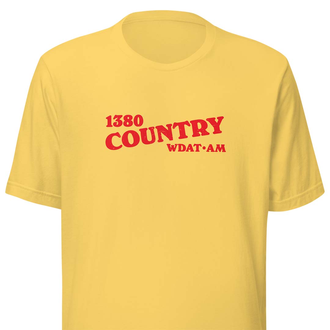 A yellow short-sleeve crewneck t-shirt with red text on the chest reading '1380 COUNTRY WDAT AM'.